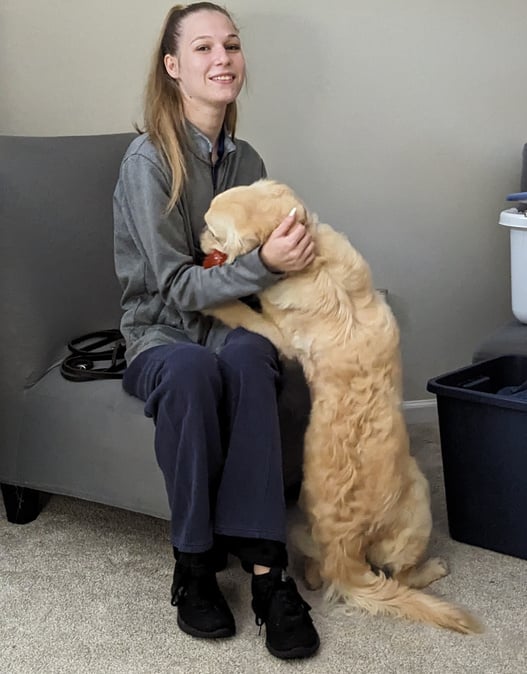 a person sitting on a chair with a dog in front of them.