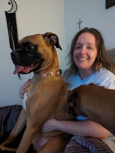 Pet sitter sitting on bed with brown dog