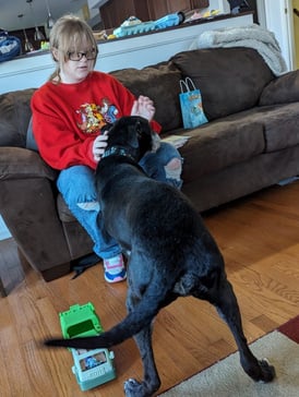 a person sitting on a couch with a black dog