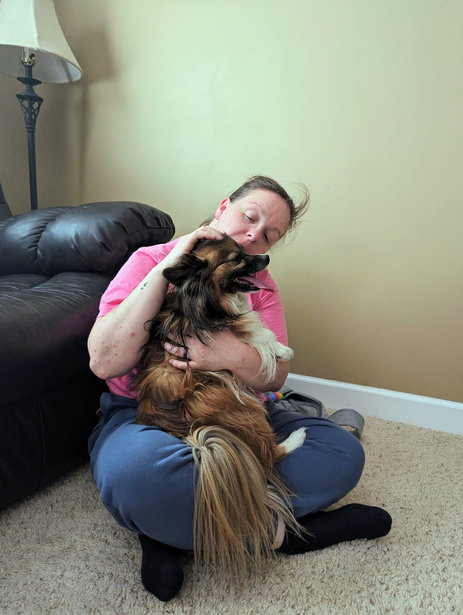 a person sitting on the floor holding a small brown dog